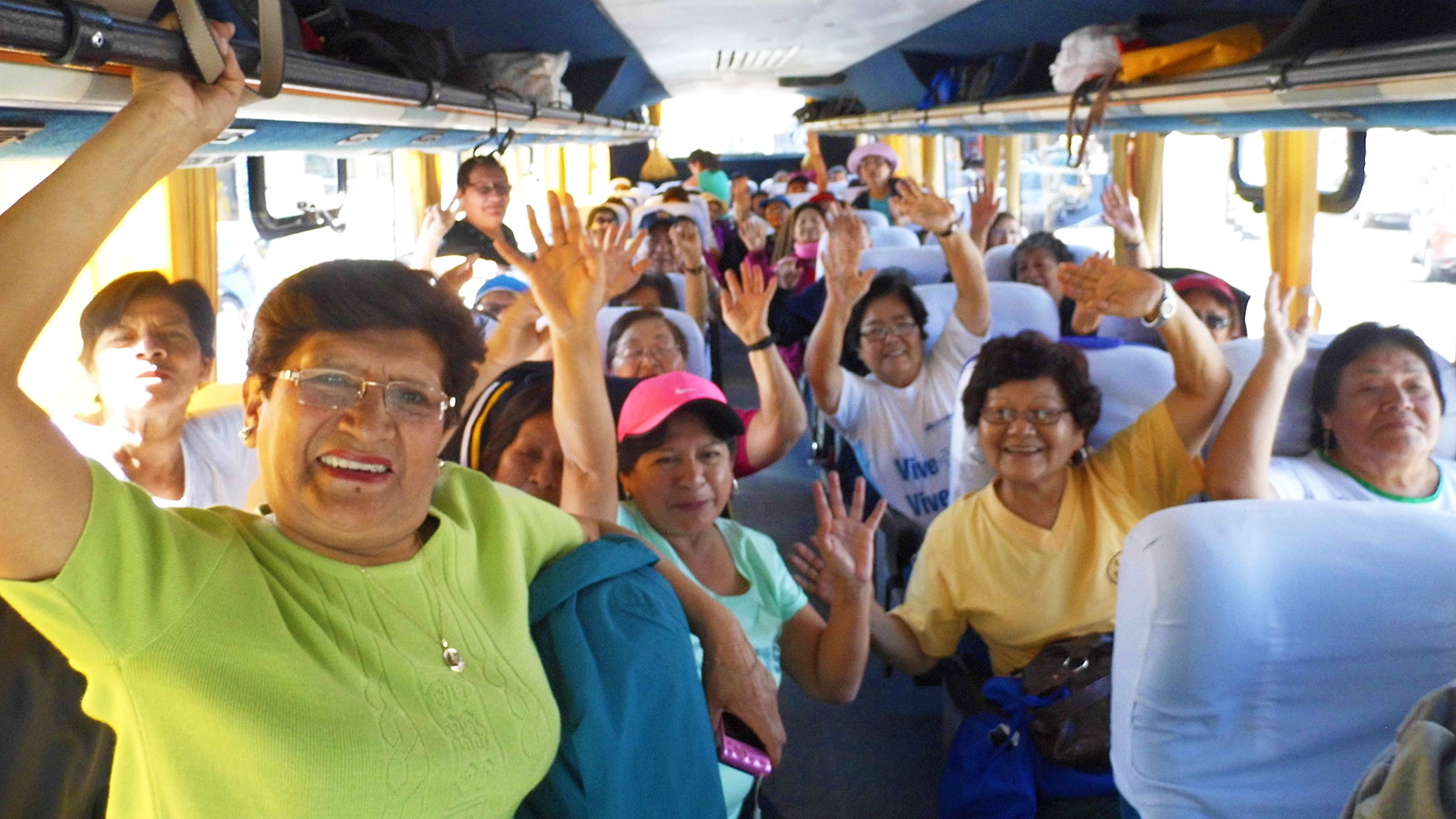 Grupo predominante de señoras sonrientes en un bus de turismo.