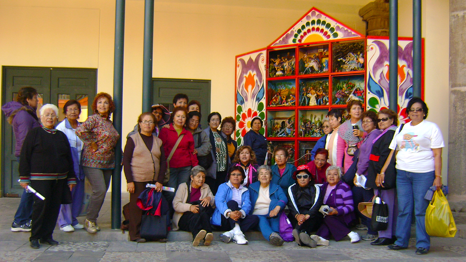 Grupo de señores ante un gigantesco retablo ayacuchano.